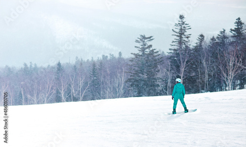 a girl on a snowboard is sliding down a mountain in the forest