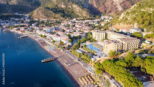 An aerial image of a beach in Turunc, Turkey. Sunrise over resort village photografed by drone. Umbrellas and sunbed in row on beach. Turunc, Turkey - September 6, 2021