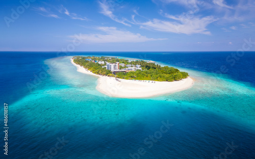 Tropical island with white beach and turquoise water in Maldives. Idyllic summer holidays vacation destination. Luxury hotel resort. Warm sunny day with blue sky. Aerial drone panorama.