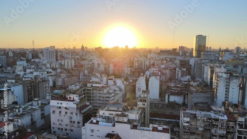 Sunset gold hours downtown cityscape of Buenos Aires, drone reverse flying revealing shot of historic furniture store, chalet museum muebles diaz perched on top of terrace building at city center.