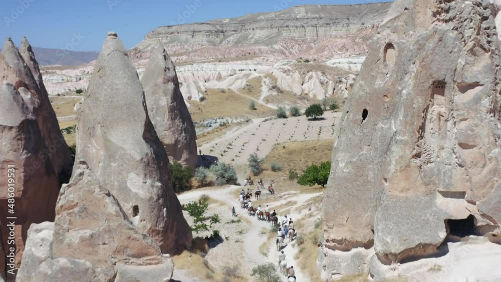 Riders with horses walking through the tufa landscape of the UNESCO World Heritage Site Goreme, Cappadocia, central Anatolia, Turkey, Asia. 4K. Aerial view Riders with horses walking through the tufa landscape of the UNESCO World Heritage Site Goreme, Cappadocia, central Anatolia, Turkey, Asia. 4K. Aerial view