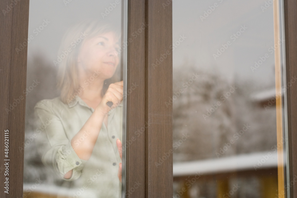 The woman is going to open the window to the street.