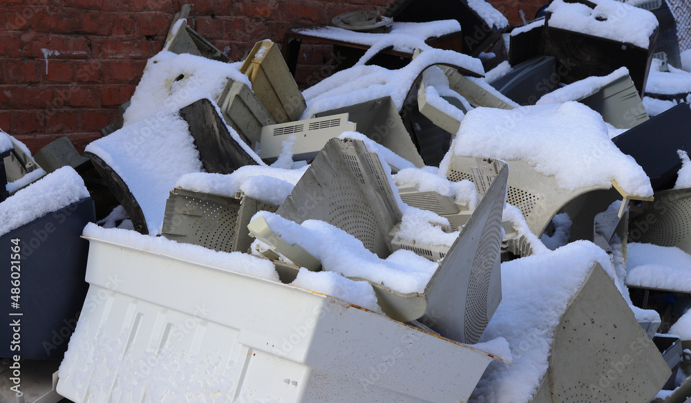 Old office equipment is covered with snow. Electronic waste consists of a monitor, printer, desktop computer and fax for reuse. Plastic, copper, glass can be reused, recycled. Environmental protection