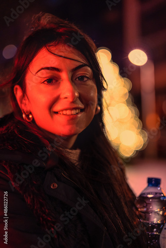 Portrait of a beautiful young woman in the street illuminated by a red spotlight. photo