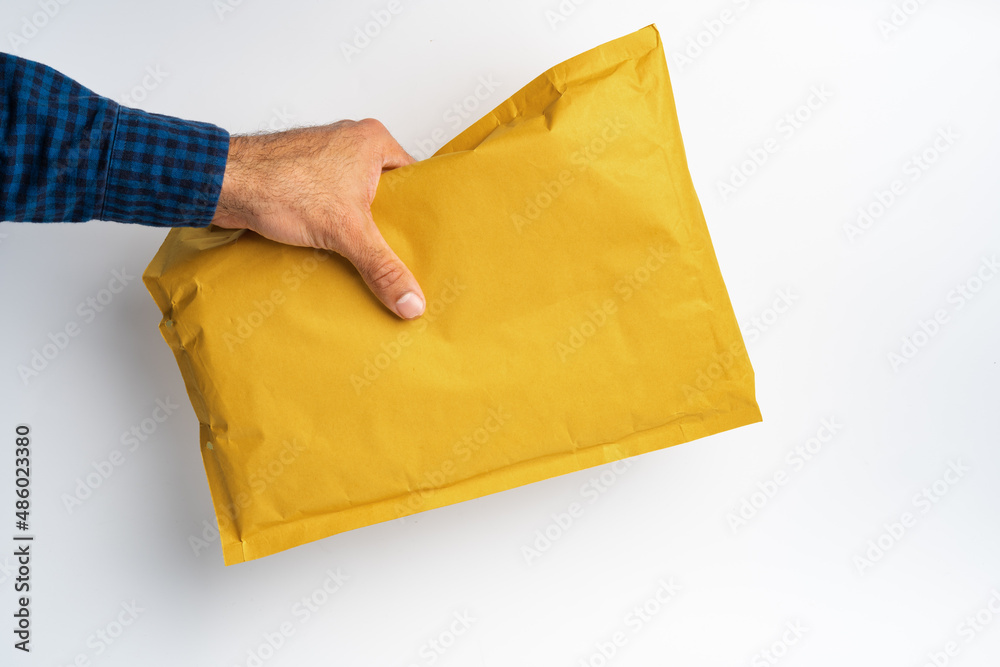 Male hand holding parcel post against white background