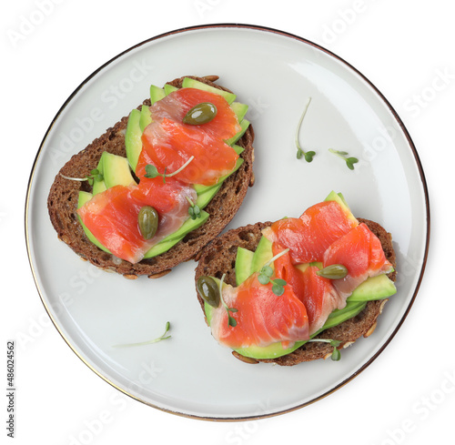 Delicious sandwiches with salmon, avocado and capers on white background, top view