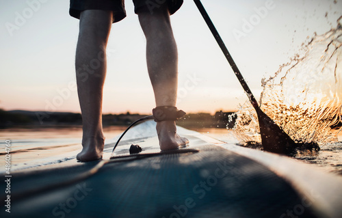 Close up of man paddleboarding at sunset  photo