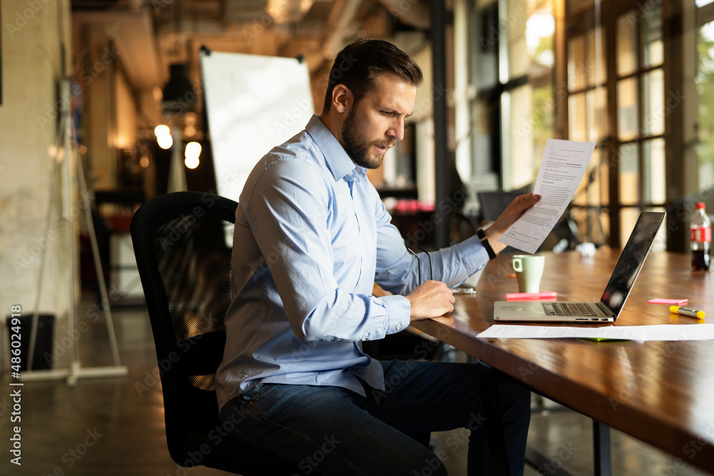 Fototapeta premium Young businessman using laptop in his office. Handsome man working on the project