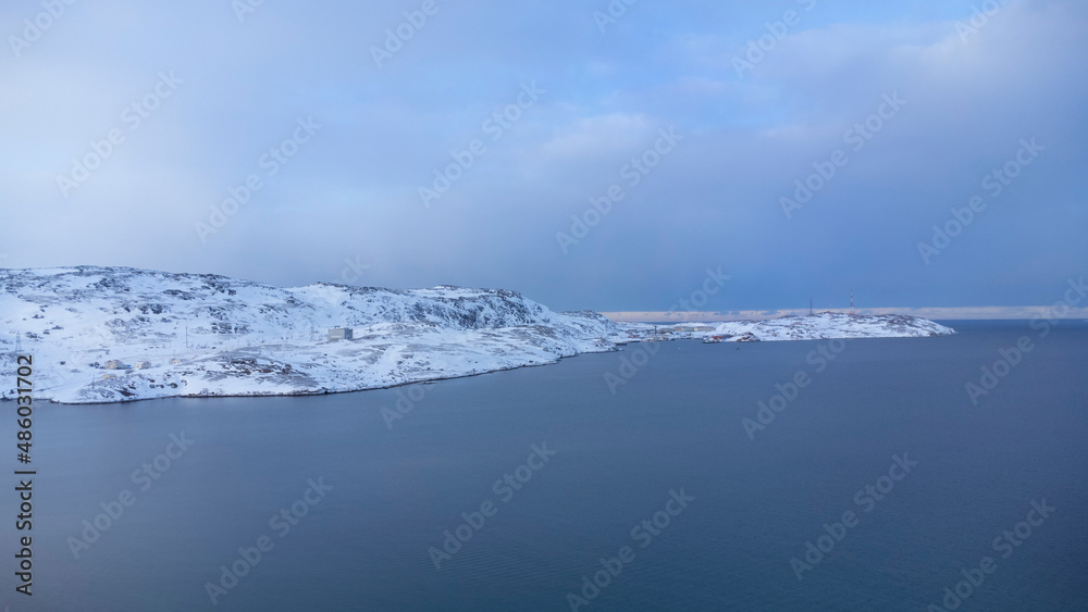 Winter seascape. A snow-covered fishing village in the far north. Sea and blue sky. Russia, Teriberka, Kola Peninsula. Top view. Winter seascape. A snow-covered fishing village in the far north. Sea and blue sky. Russia, Teriberka, Kola Peninsula. Top view.