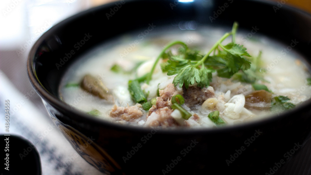 Pork boiled rice with shiitake mushrooms on a black bowl with a spoon on the table. Pork boiled rice with shiitake mushrooms on a black bowl with a spoon on the table.