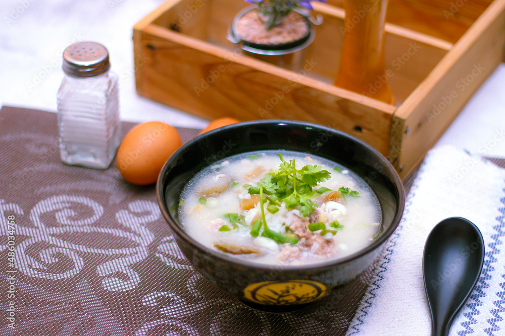 Pork boiled rice with shiitake mushrooms on a black bowl with a spoon on the table. Pork boiled rice with shiitake mushrooms on a black bowl with a spoon on the table.