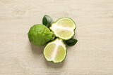 Whole and cut ripe bergamot fruits with green leaves on white wooden table, flat lay