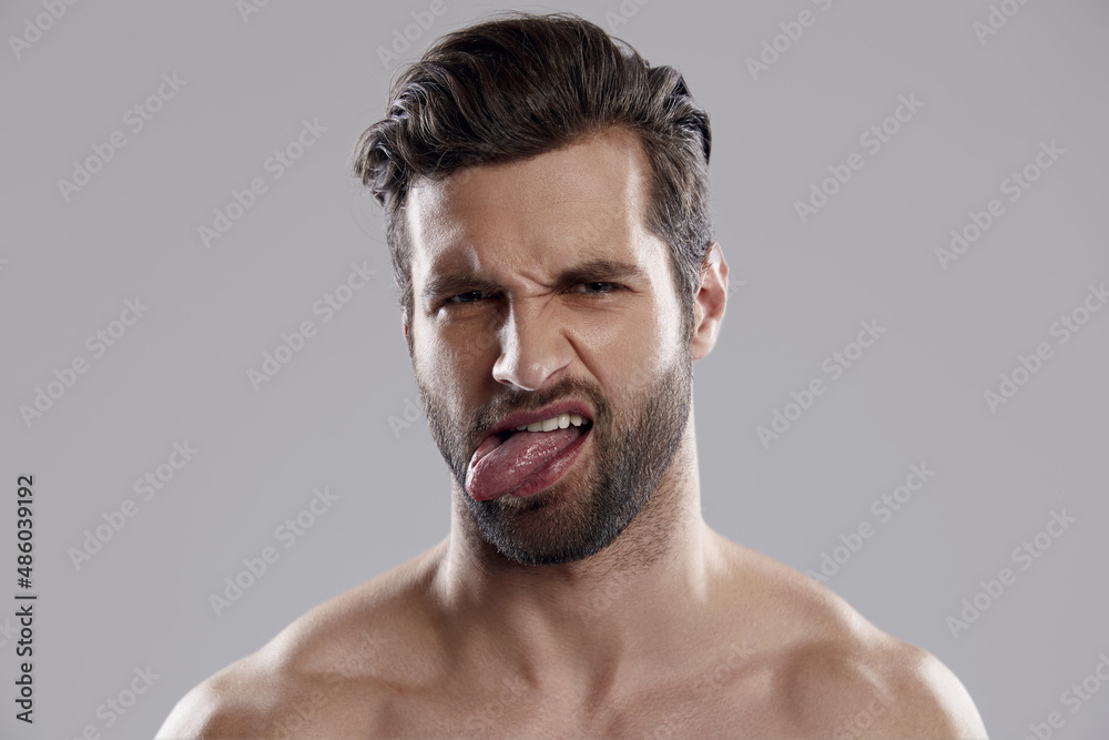 Dissatisfied man showing face grimace with tongue Dissatisfied man showing face grimace with tongue