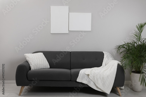 Fototapeta Naklejka Na Ścianę i Meble -  Blank canvas on wall over comfortable sofa indoors. Space for design