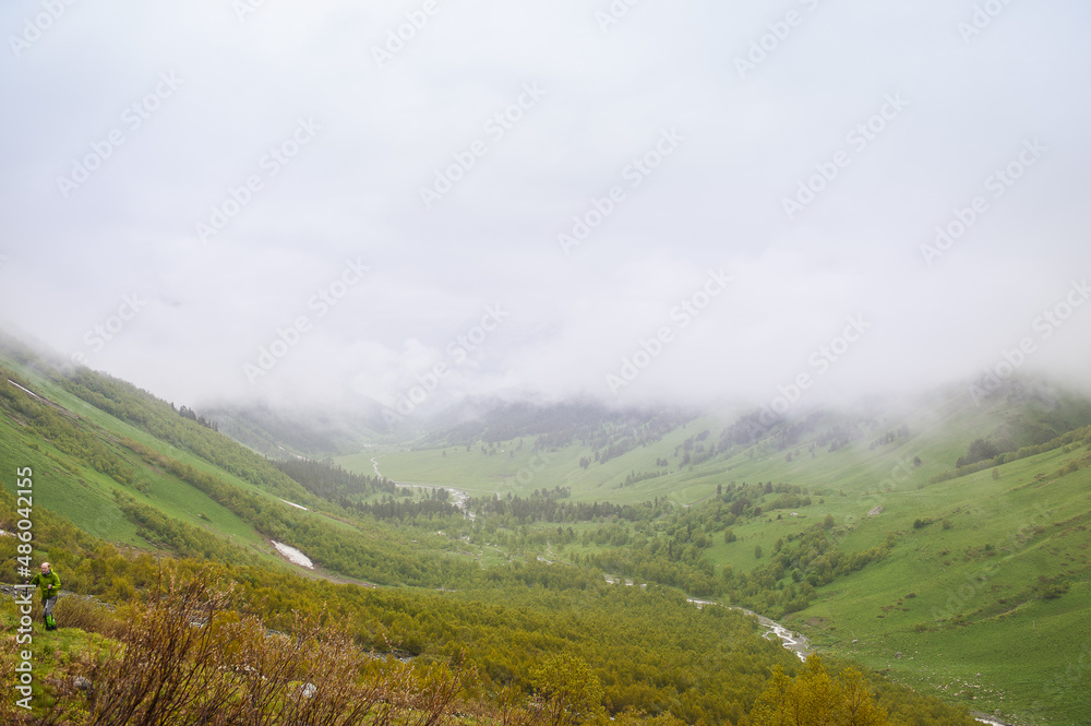 Beautiful landscape with meadow valley and fog clouds