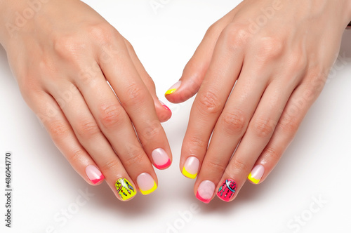 Bright, summer nail design. French colored yellow, coral manicure on short square nails close-up on a white background. Painted dream catcher on the ring fingers.