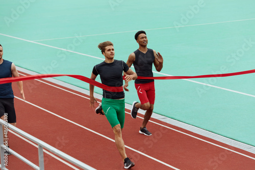 Sportsmen run on finish on treadmill on stadium © Drobot Dean