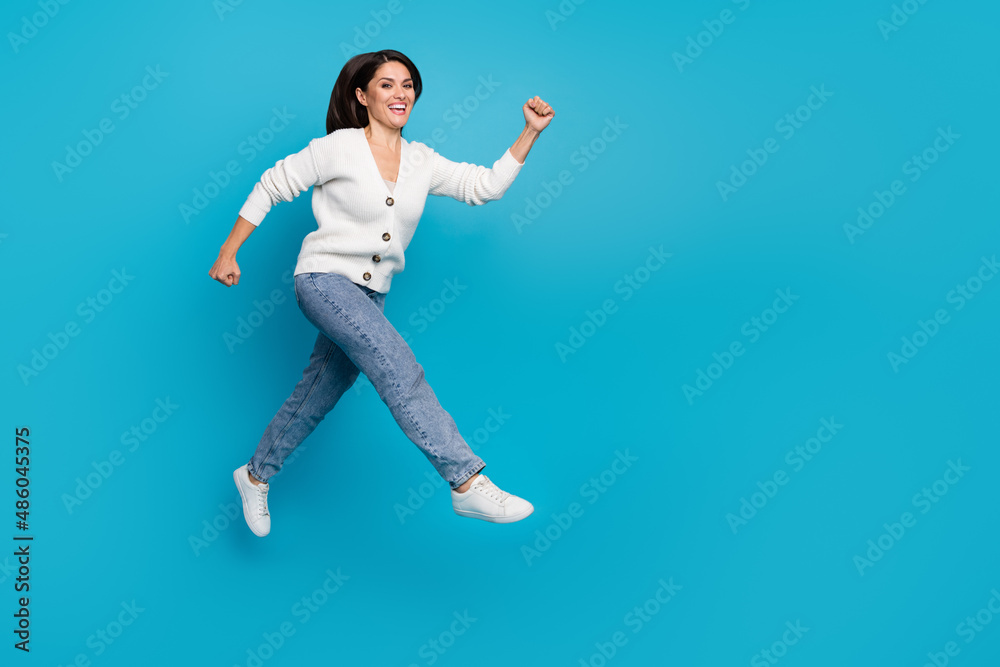 Photo of sweet charming woman wear white cardigan running fast jumping high isolated blue color background