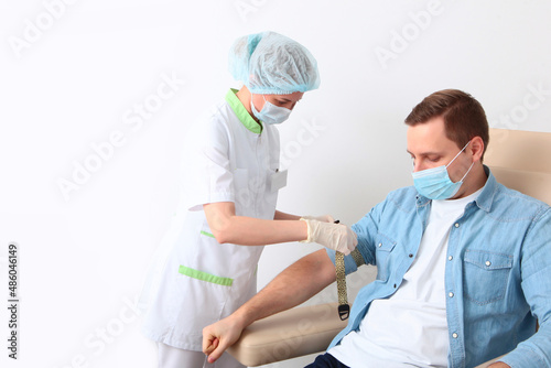 A man donates blood in a medical laboratory. A general blood test. Nurse and patient. The concept of healthcare.Copy space.