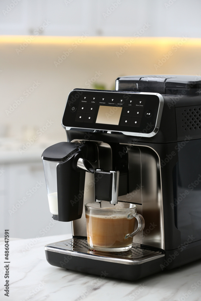 Modern espresso machine and glass cup of coffee with milk on white marble countertop in kitchen Modern espresso machine and glass cup of coffee with milk on white marble countertop in kitchen