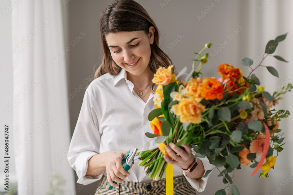 people, gardening and floral design concept - happy smiling woman or floral artist making bunch of flowers and cutting stems with pruning shears at home people, gardening and floral design concept - happy smiling woman or floral artist making bunch of flowers and cutting stems with pruning shears at home