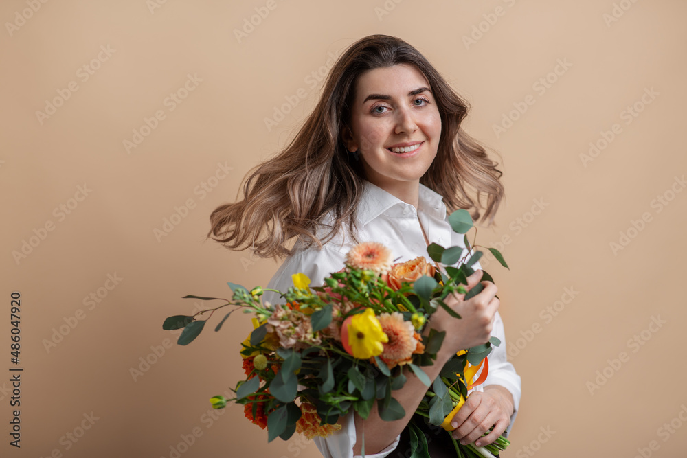 people and floral design concept - portrait of happy smiling woman holding bunch of flowers over beige background