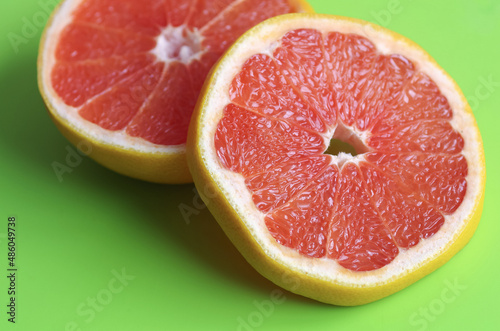 Sliced ​​grapefruit on a green background. Ripe and juicy citrus.