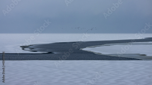 Beautiful huge lake on a cloudy day. The surface of the lake with a crack in the water. Winter period photo