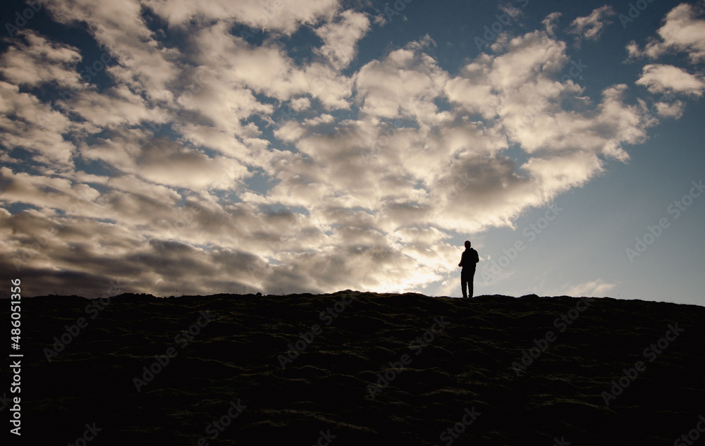 silhouette of a person on a mountain top with clouds