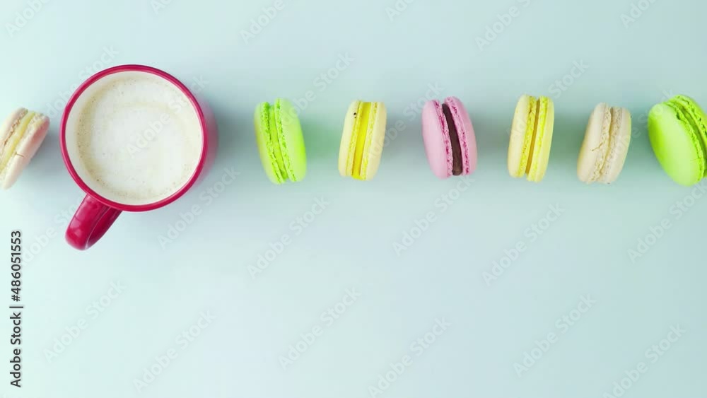 Top view of multicolored French Macarons cookies and a cup of coffee on a pastel blue background Top view of multicolored French Macarons cookies and a cup of coffee on a pastel blue background