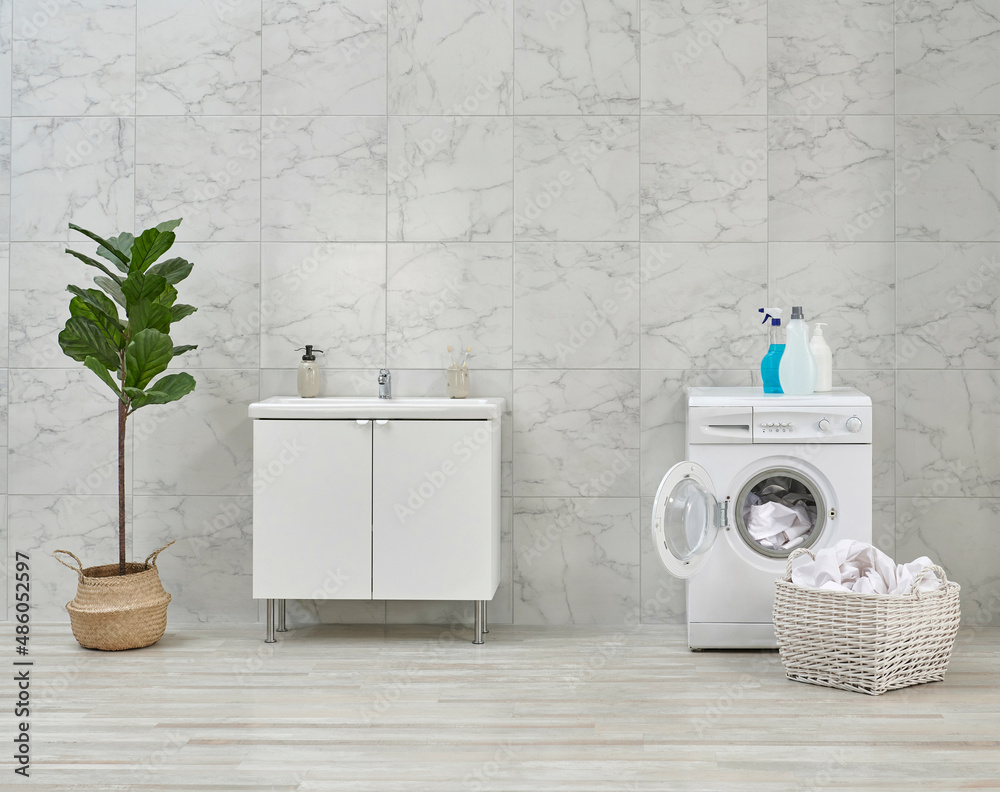 Washing machine and cabinet and sink in the white bathroom, cleaning materials, dirty clothes in the basket style. Washing machine and cabinet and sink in the white bathroom, cleaning materials, dirty clothes in the basket style.