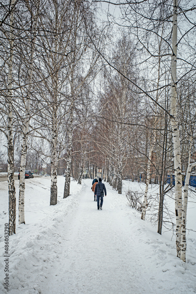 Citizens walk along the snow-covered sidewalk on a winter day