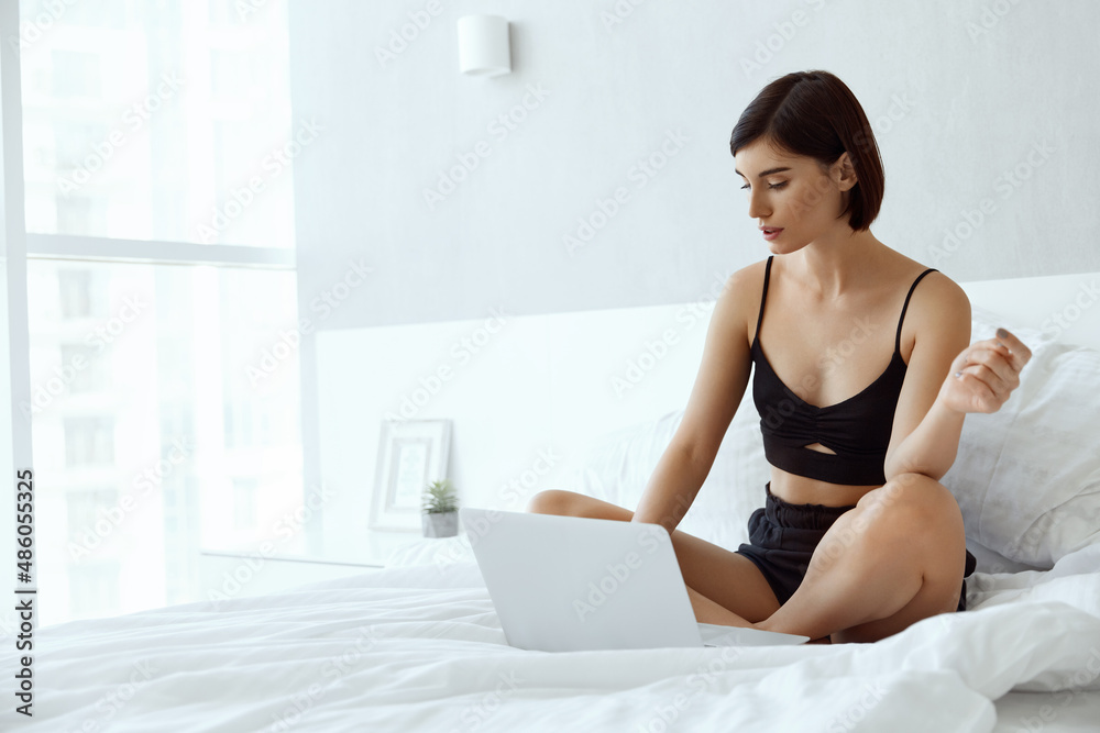 Young caucasian girl using laptop on bed at home Young caucasian girl using laptop on bed at home