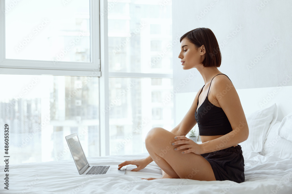 Young caucasian girl using laptop on bed at home Young caucasian girl using laptop on bed at home