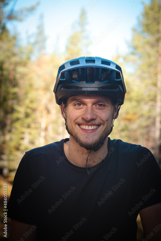 recreational cyclist smiles with satisfaction after a challenging trail in the mud. Candid portrait of a young athlete with a real smile and mud on his face