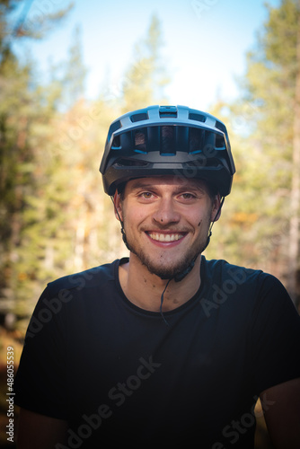 recreational cyclist smiles with satisfaction after a challenging trail in the mud. Candid portrait of a young athlete with a real smile and mud on his face © Fauren