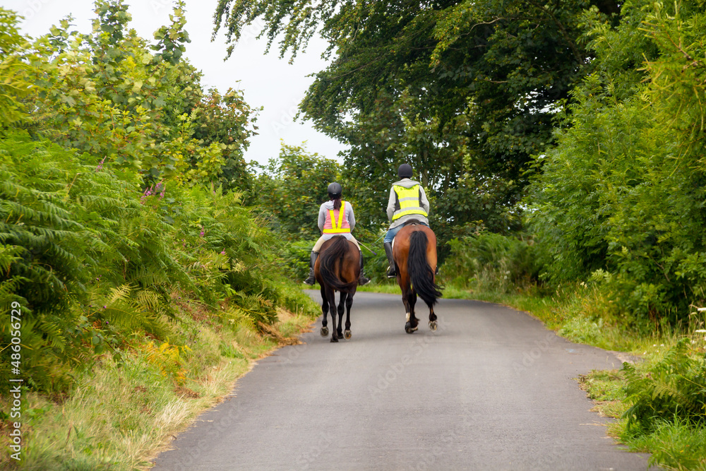 Couple riding along country roads in rural Wales, wearing bright safety gear to be seen and keep themselves and other road users safe. Couple riding along country roads in rural Wales, wearing bright safety gear to be seen and keep themselves and other road users safe.