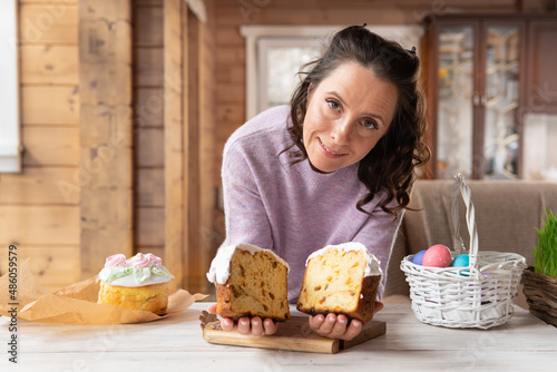 A woman holds a traditional Easter cake on the table.