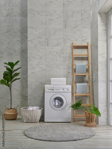 Washing machine decorative style in the bath room, vase of plant, mirror and wooden stairs, towel and brush, dirty clothes in wicker basket.