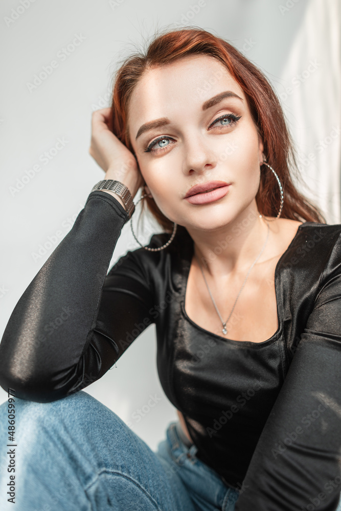 Beautiful woman in casual fashion clothes sits in white room with sunlight. Amazing blue female eyes Beautiful woman in casual fashion clothes sits in white room with sunlight. Amazing blue female eyes