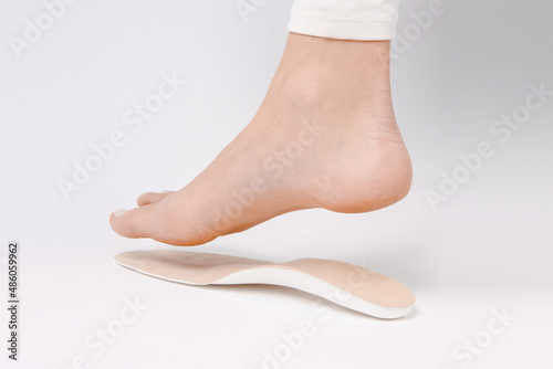 Medical insoles. Isolated orthopedic insoles on a white background. Foot care. Insole cutaway layers. Leg hanging over the insole. Treatment and prevention of flat feet and foot diseases. photo