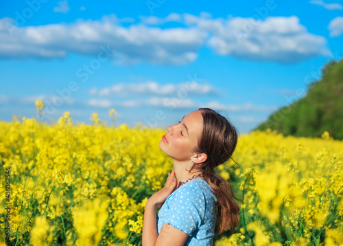 Beautiful teen girl is smiling with yellow flowers in summer field