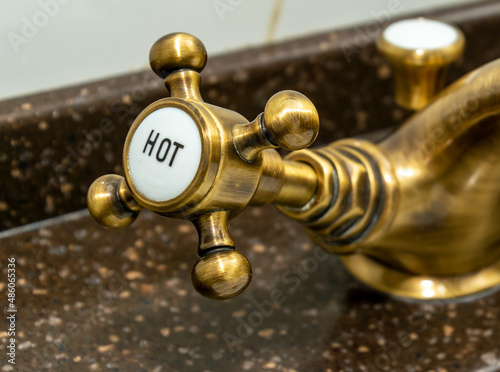 Copper faucet in hotel shower room, focus on hot water faucet