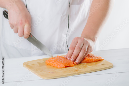 the chef cuts salmon on a wooden board, on a white background