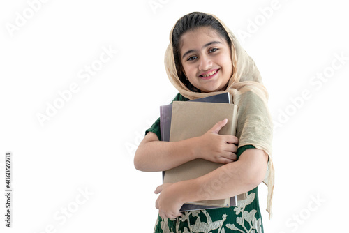 Smiling schoolgirl with her book,  Little Indian or Pakistan girl wearing traditional costume on white background, with clipping path