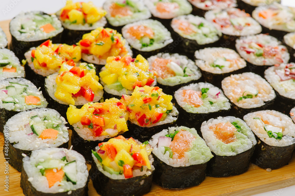 Maki Sushi Rolls set on wooden board. Japanese traditional Cuisine. White background. Maki Sushi Rolls set on wooden board. Japanese traditional Cuisine. White background.
