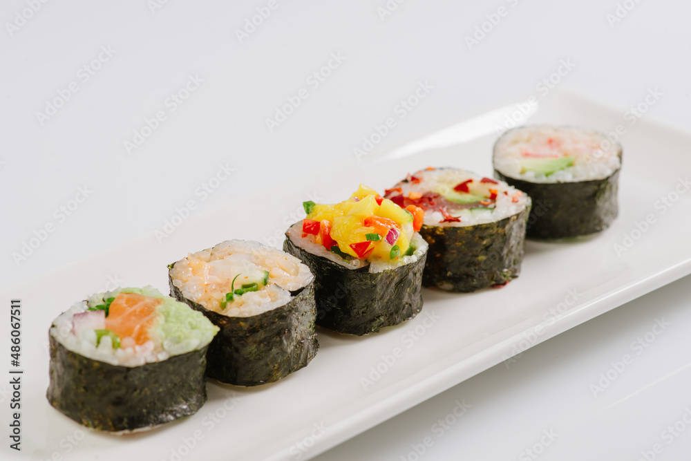Sushi with chopsticks on a white plate. Sushi roll japanese food in restaurant isolated on white background. Fresh hosomaki pieces with rice and nori. Sushi with chopsticks on a white plate. Sushi roll japanese food in restaurant isolated on white background. Fresh hosomaki pieces with rice and nori.