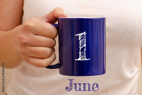 The inscription on the blue cup 1 june. Cup in female hand, business concept