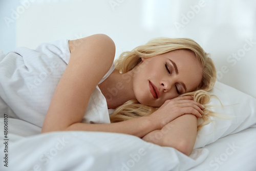 Beautiful blonde girl sleep under blanket on bed