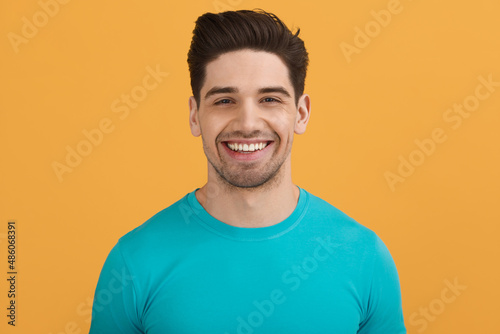Young caucasian man on orange background in studio